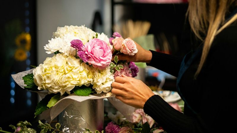 A woman arranging flowers in a vase on a table