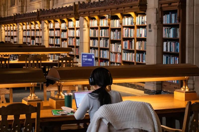 도서관에서 책과 노트를 펼쳐놓고 공부하는 대학생