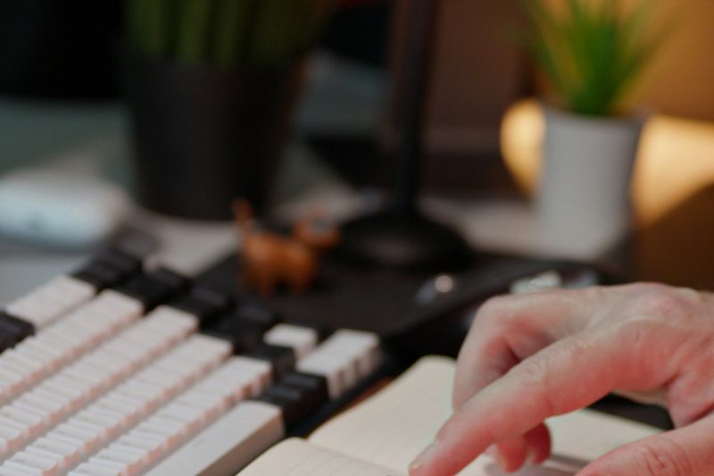 A hand checking off a to-do list in a notebook next to a keyboard