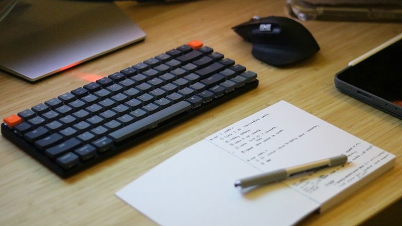 A tidy desk with a keyboard and a notebook full of handwritten notes