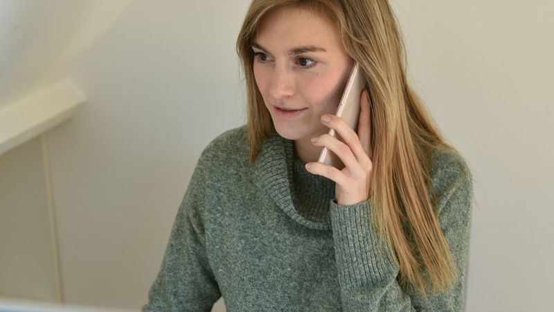 A woman at a computer on a phone call with a client