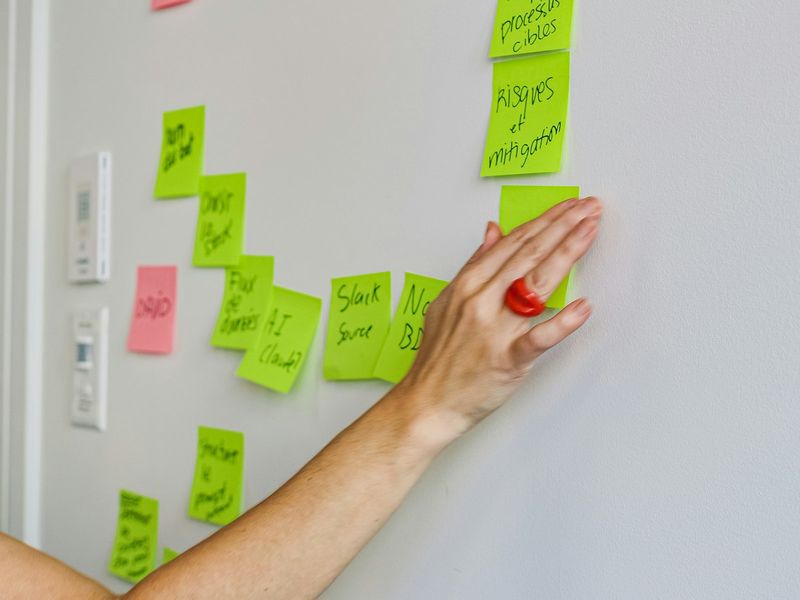A hand placing a sticky note on a green wall