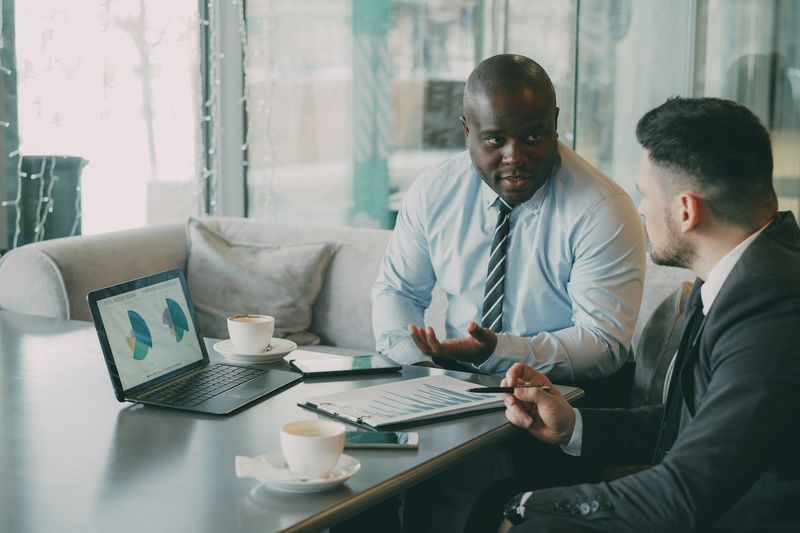 Two people discussing charts on a laptop screen