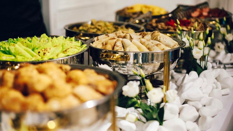 A buffet table with silver chafing dishes filled with food