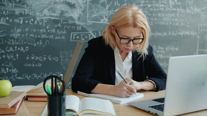 A woman writing notes in a notebook at a desk