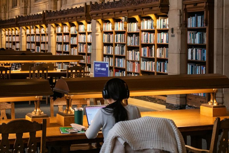 도서관 책상에서 책을 펼쳐 놓고 공부하는 학생