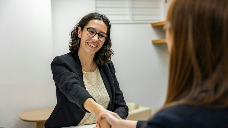 An interviewer and a candidate shaking hands at a table