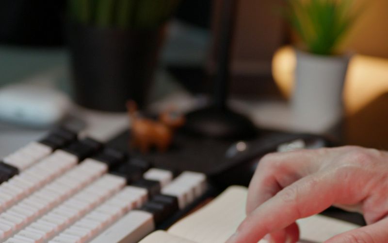Person checking a handwritten to-do list in a notebook next to a keyboard