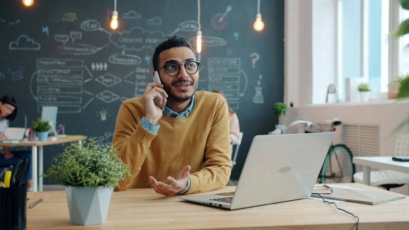 A man on a call with a customer at his desk in front of a laptop