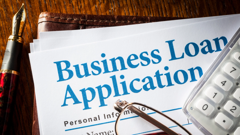 Business loan application form on a desk with pen, calculator, and eyeglasses, representing business loans, financing, and cash flow management.