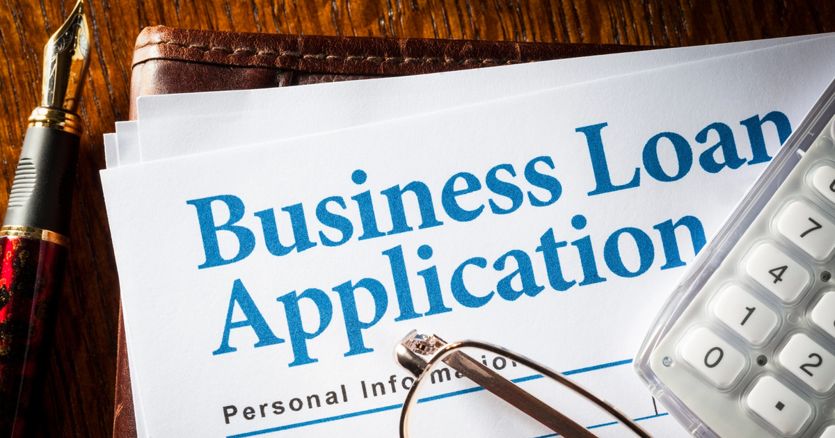 Business loan application form on a desk with pen, calculator, and eyeglasses, representing business loans, financing, and cash flow management.
