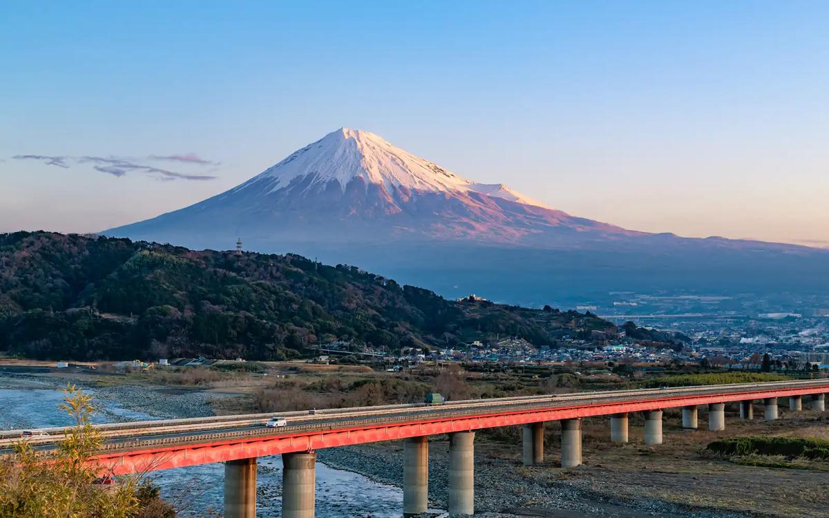 Mount Fuji with red bridge, river, and surrounding landscape at sunrise
