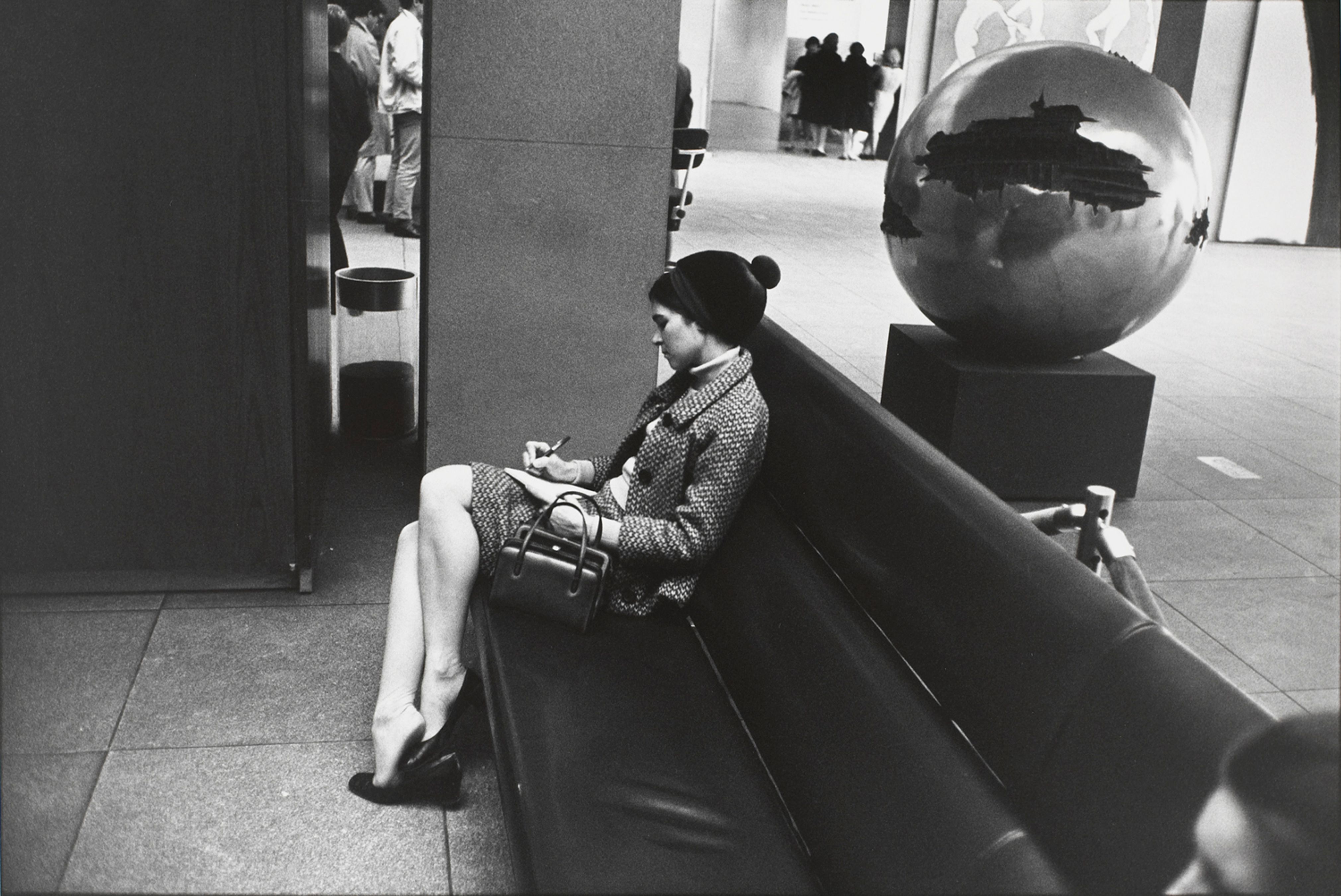 Untitled (Woman seated on black couch, in dark suit, writing)