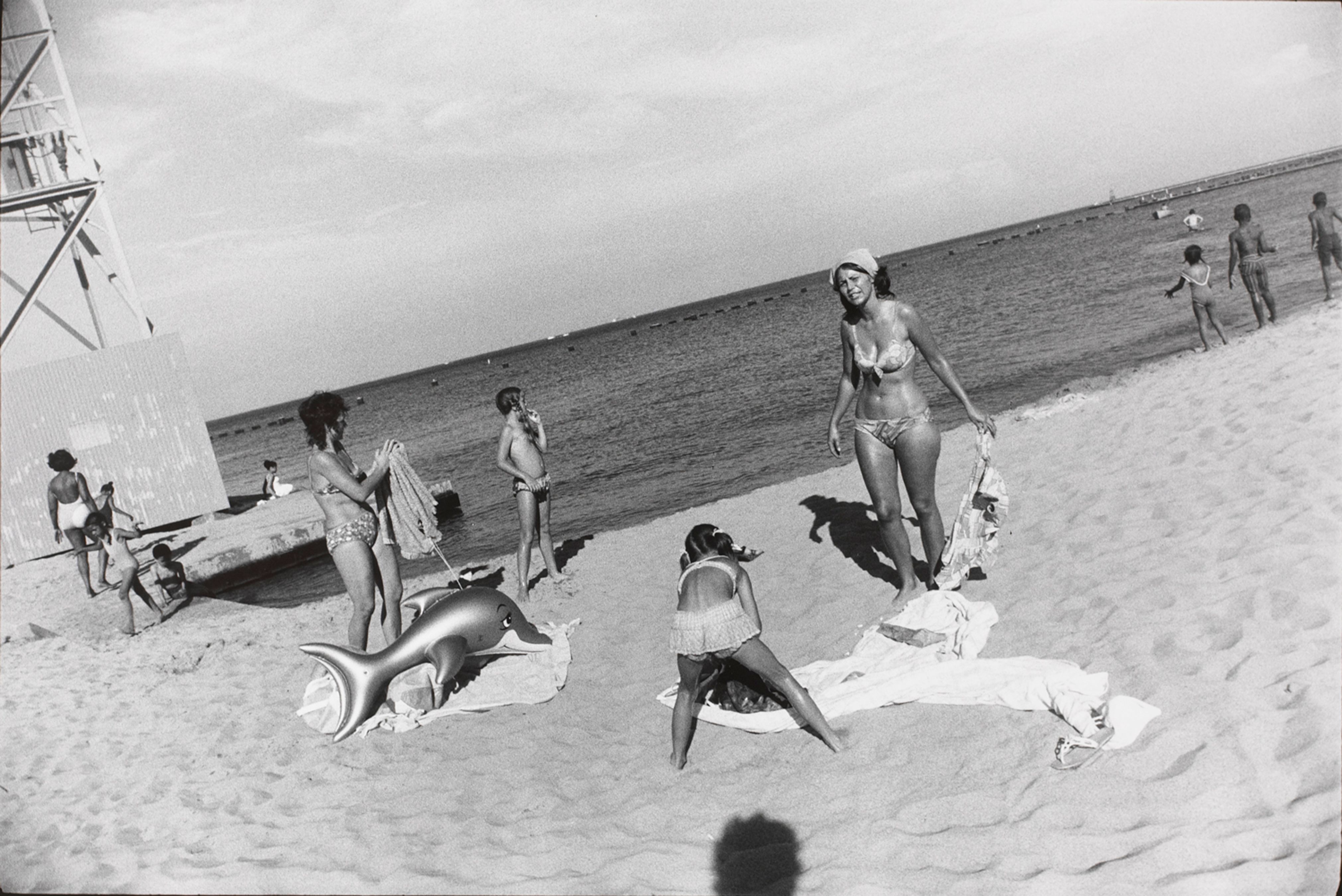 Untitled (Two women on a beach with a child and a blow up dolphin toy)