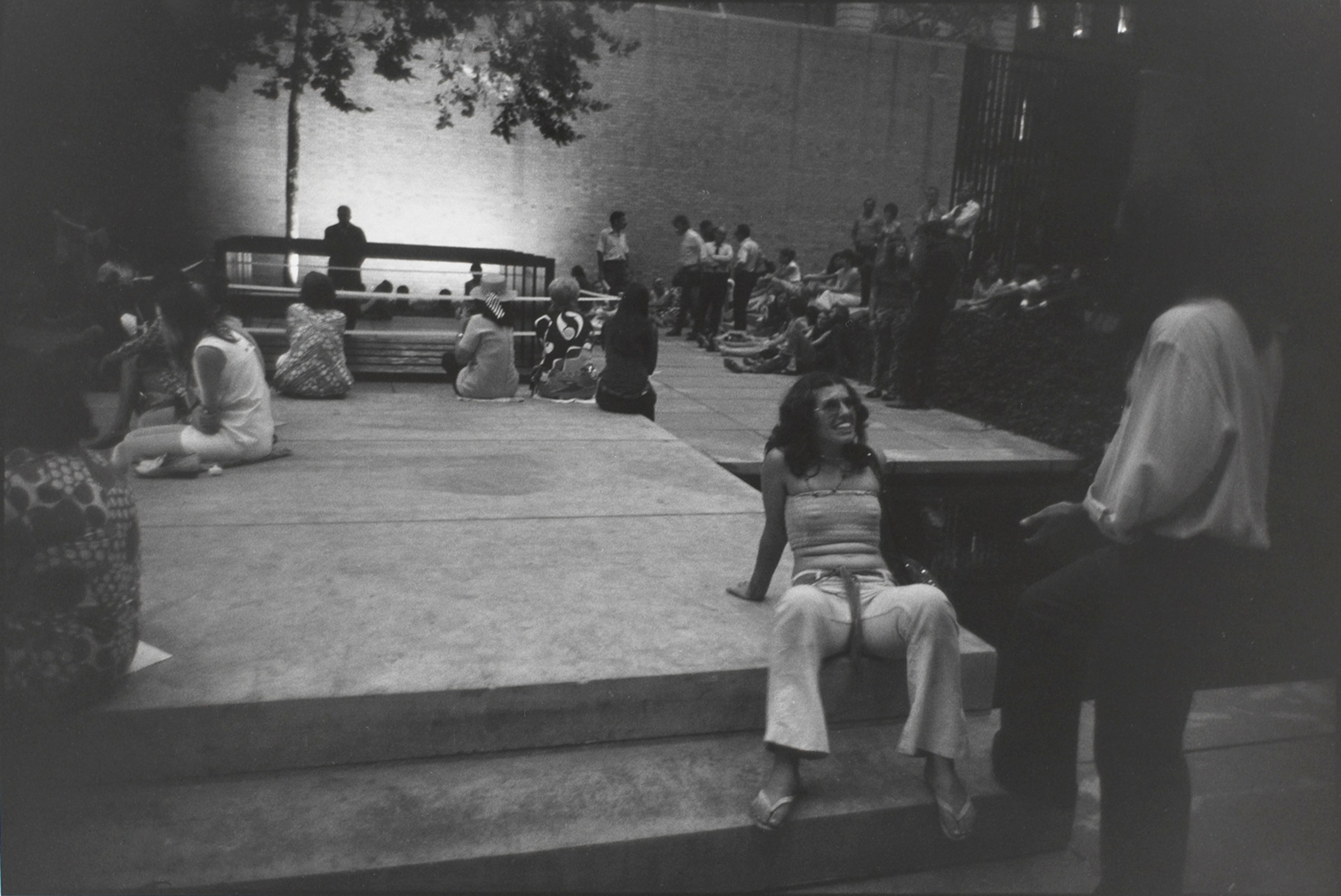 Untitled (People gathered in MOMA’s outdoor courtyard, woman seated smiling up at a man)