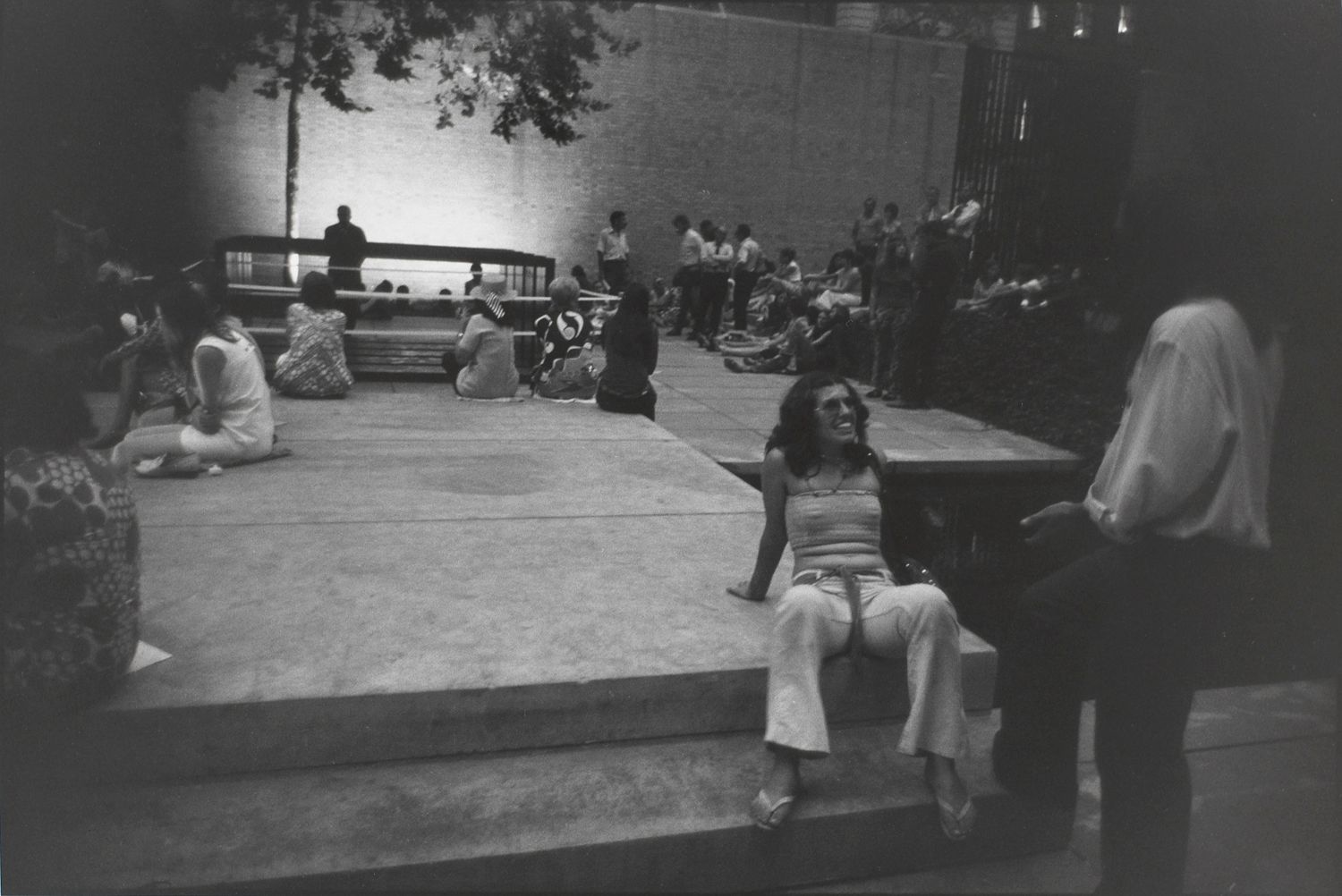 Untitled (People gathered in MOMA’s outdoor courtyard, woman seated smiling up at a man)