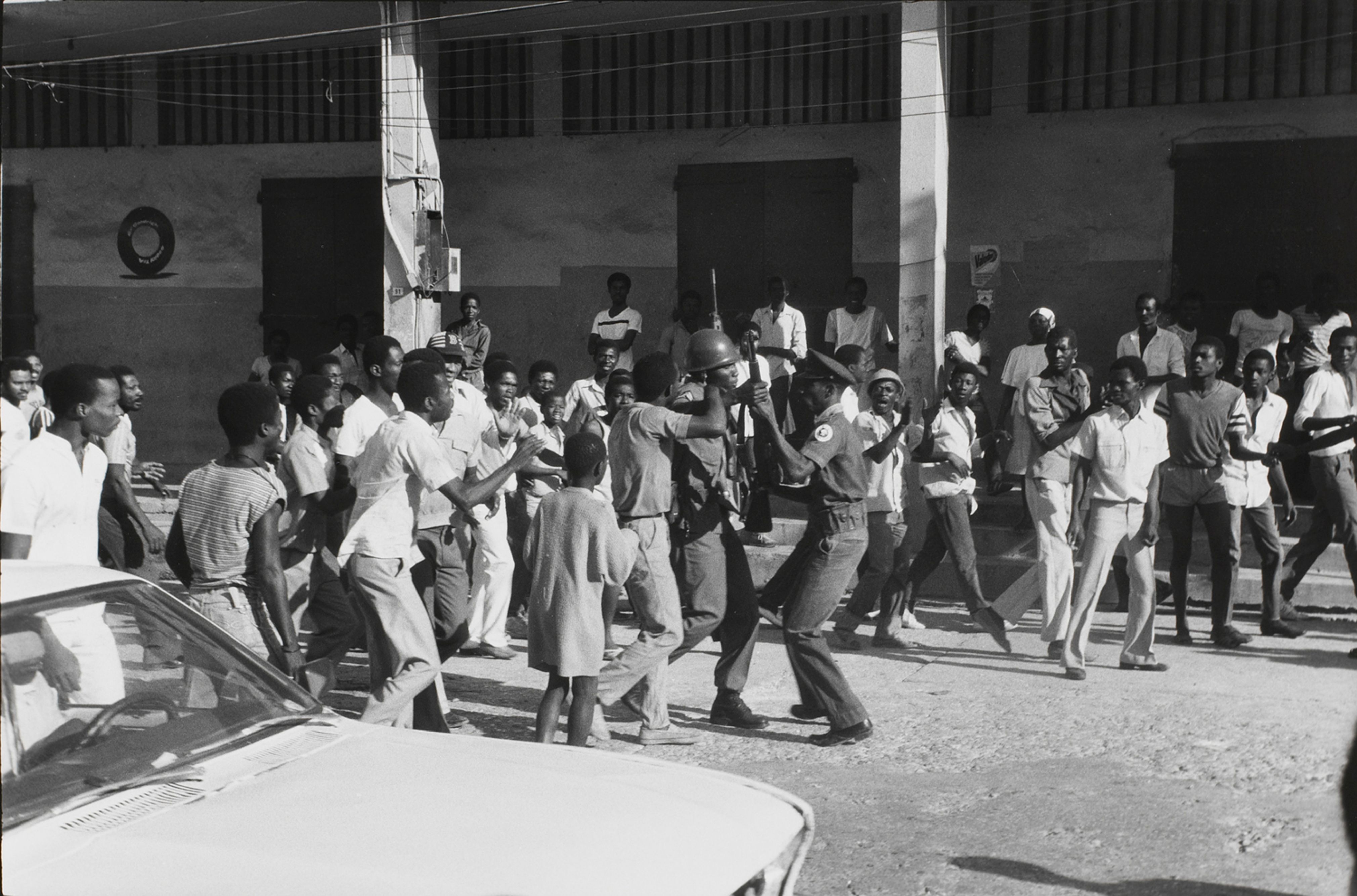 Dawn on February 7th. As news spreads that Jean-Claude Duvalier is gone, a soldier disarms a Tonton Macoute