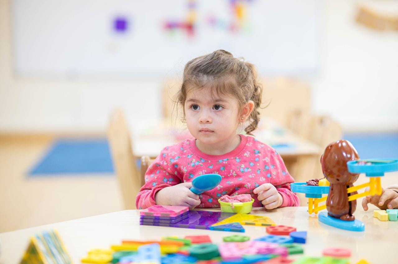 A child playing with shapes and counting toys at the table