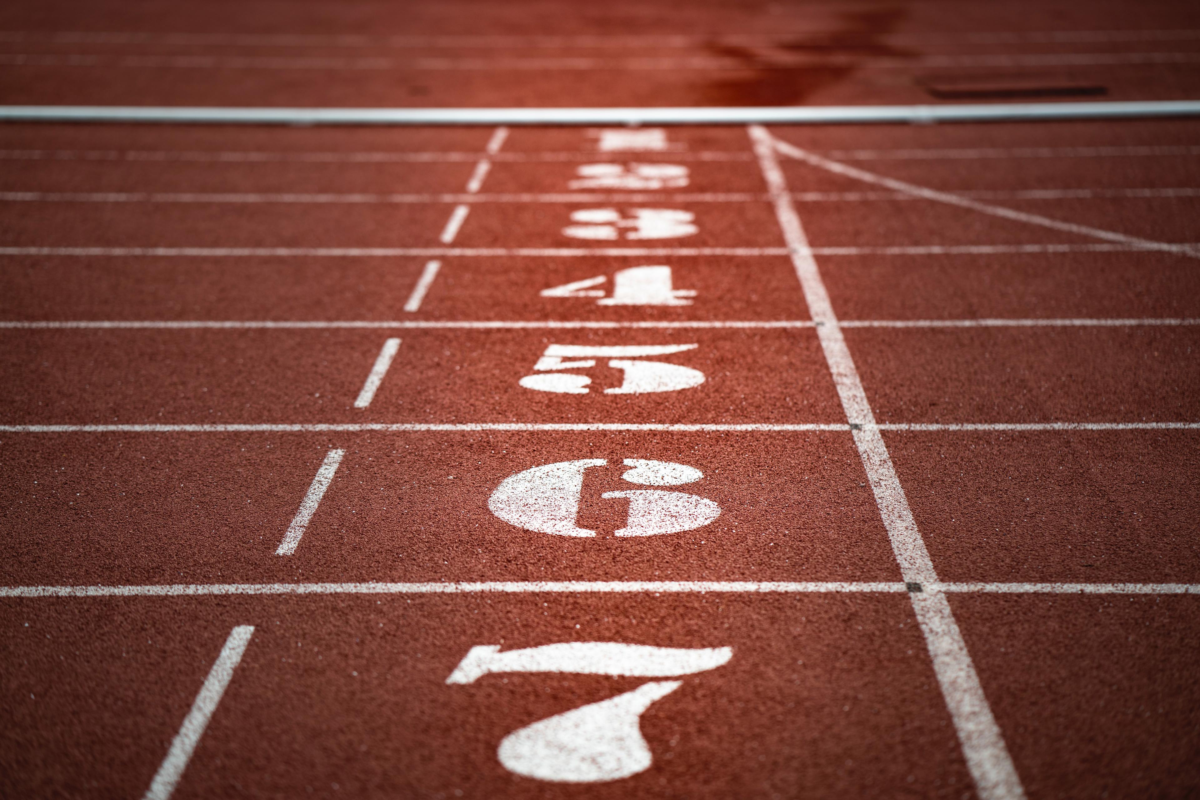 A photo of a rust-red running track, with numbers from 6 to 1