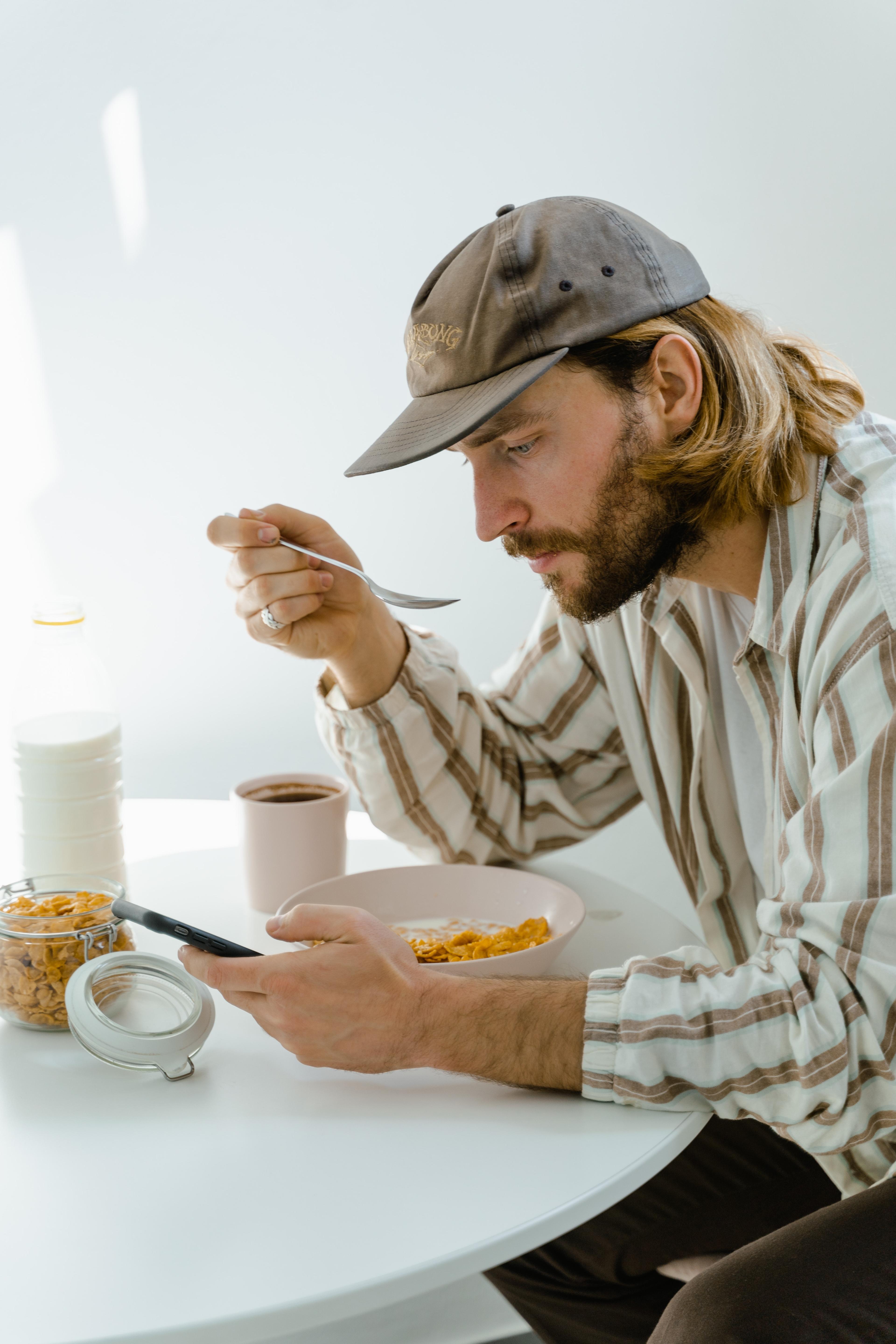 Man sitting on his phone eating cereal