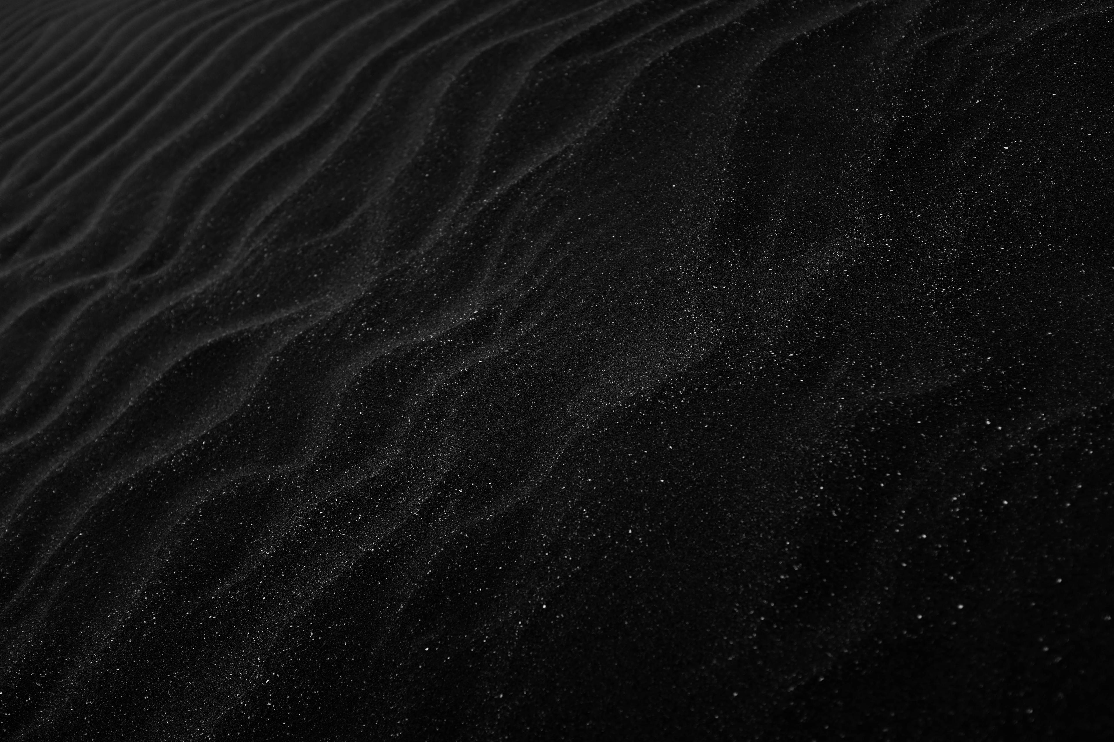 An overhead view of black waves of sand