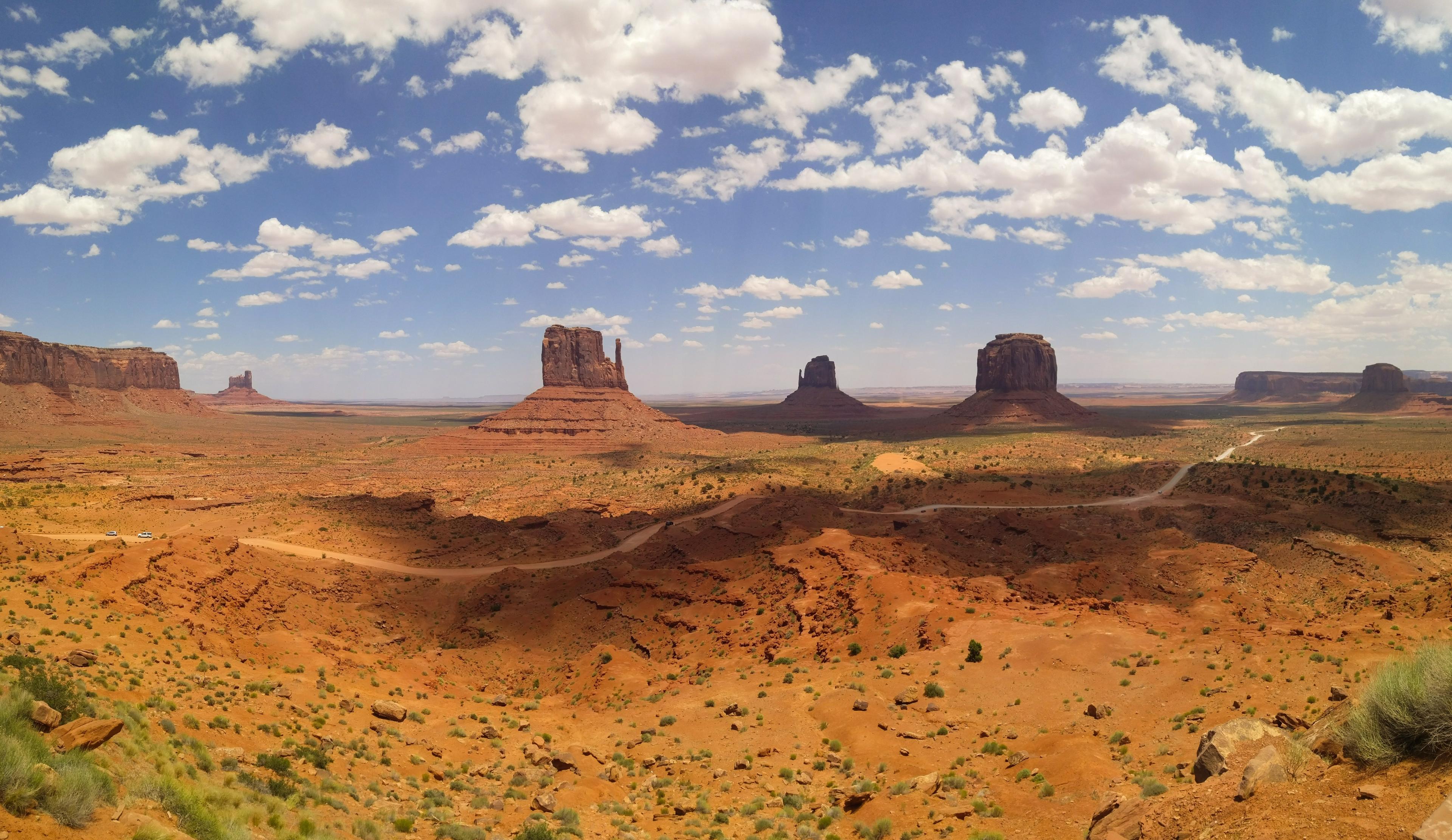 A southwestern landscape, with rock formations and white clouds in a blue sky