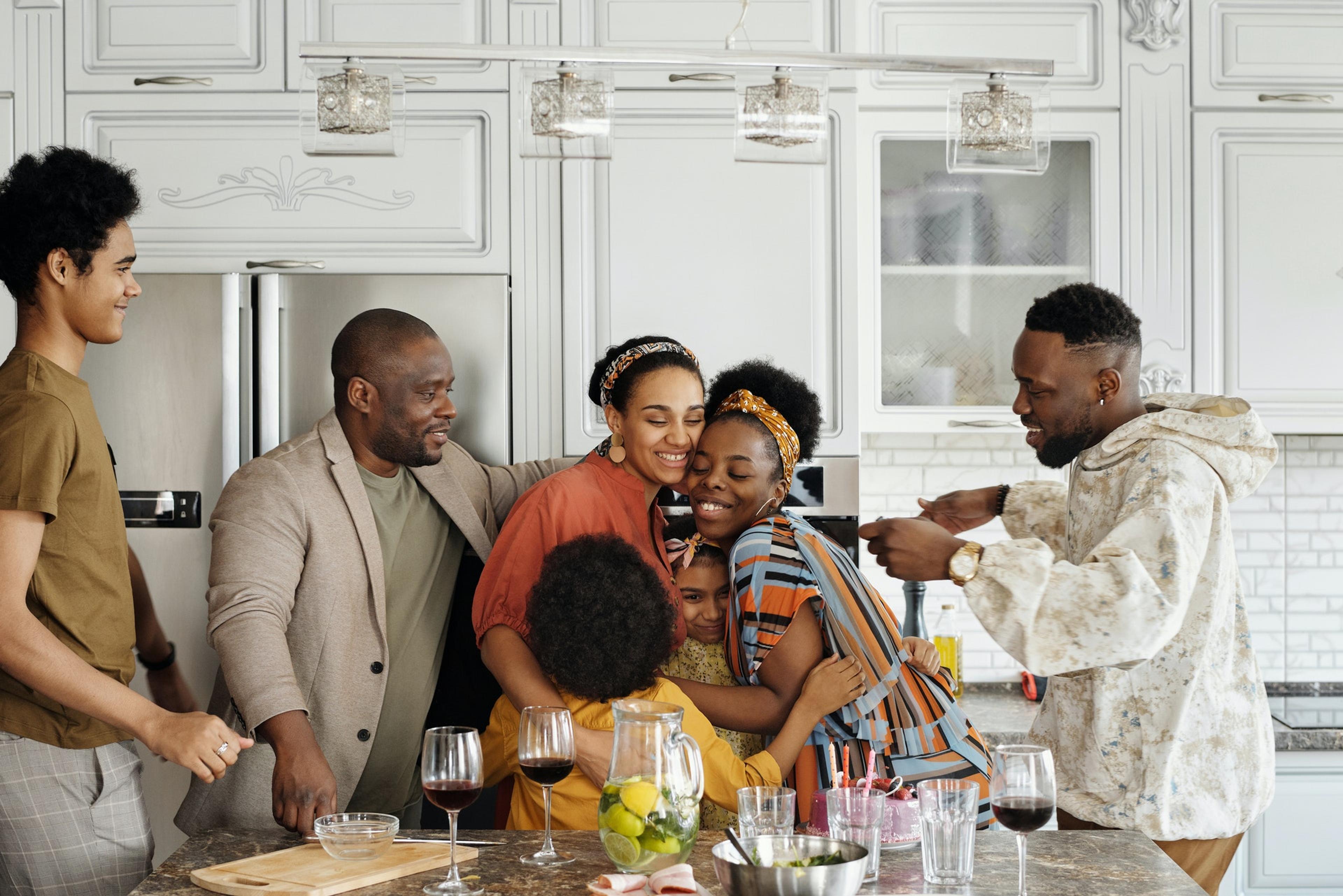 A Black family embraces in the kitchen around an island counter