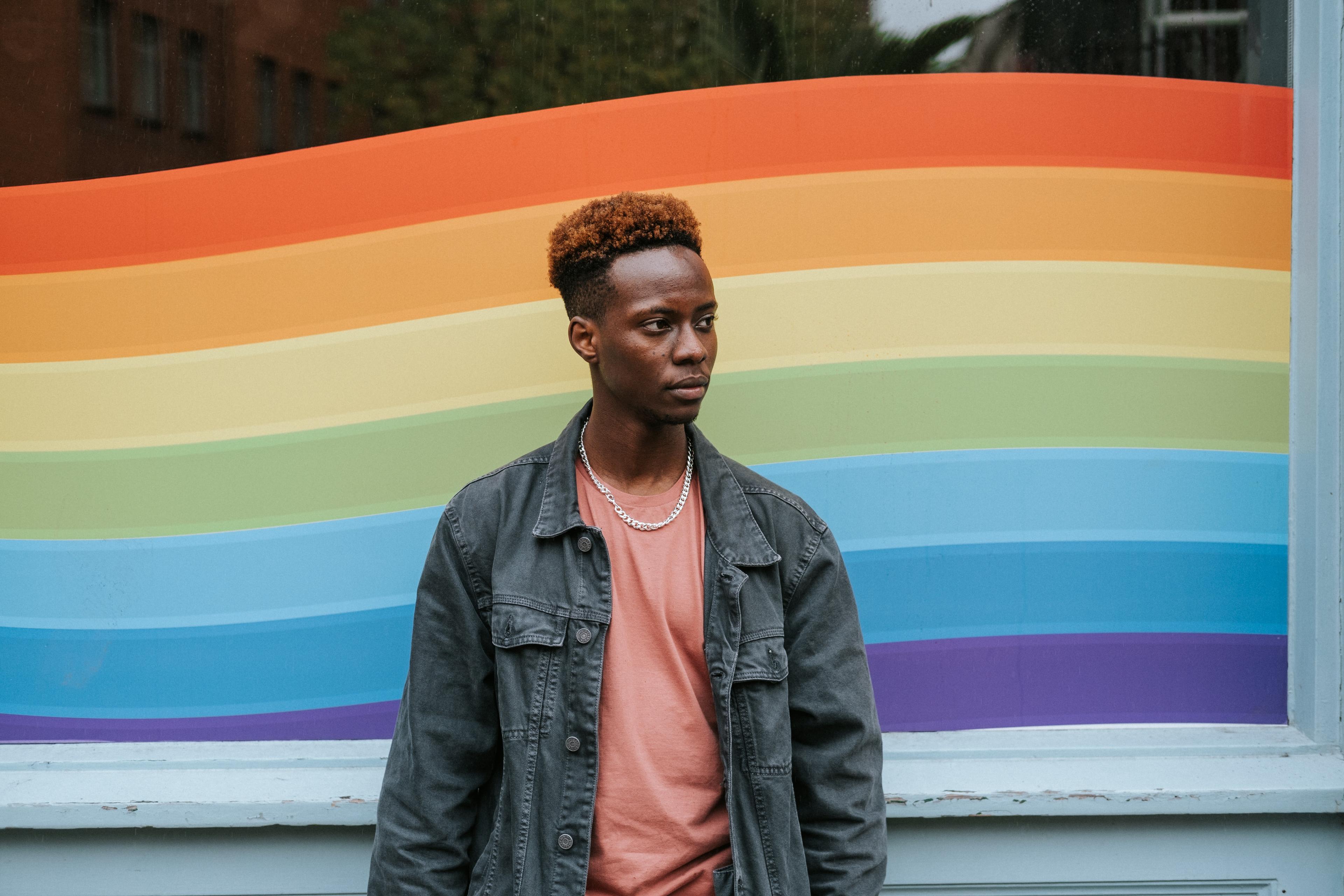 Contemplative man standing in front of pride colors