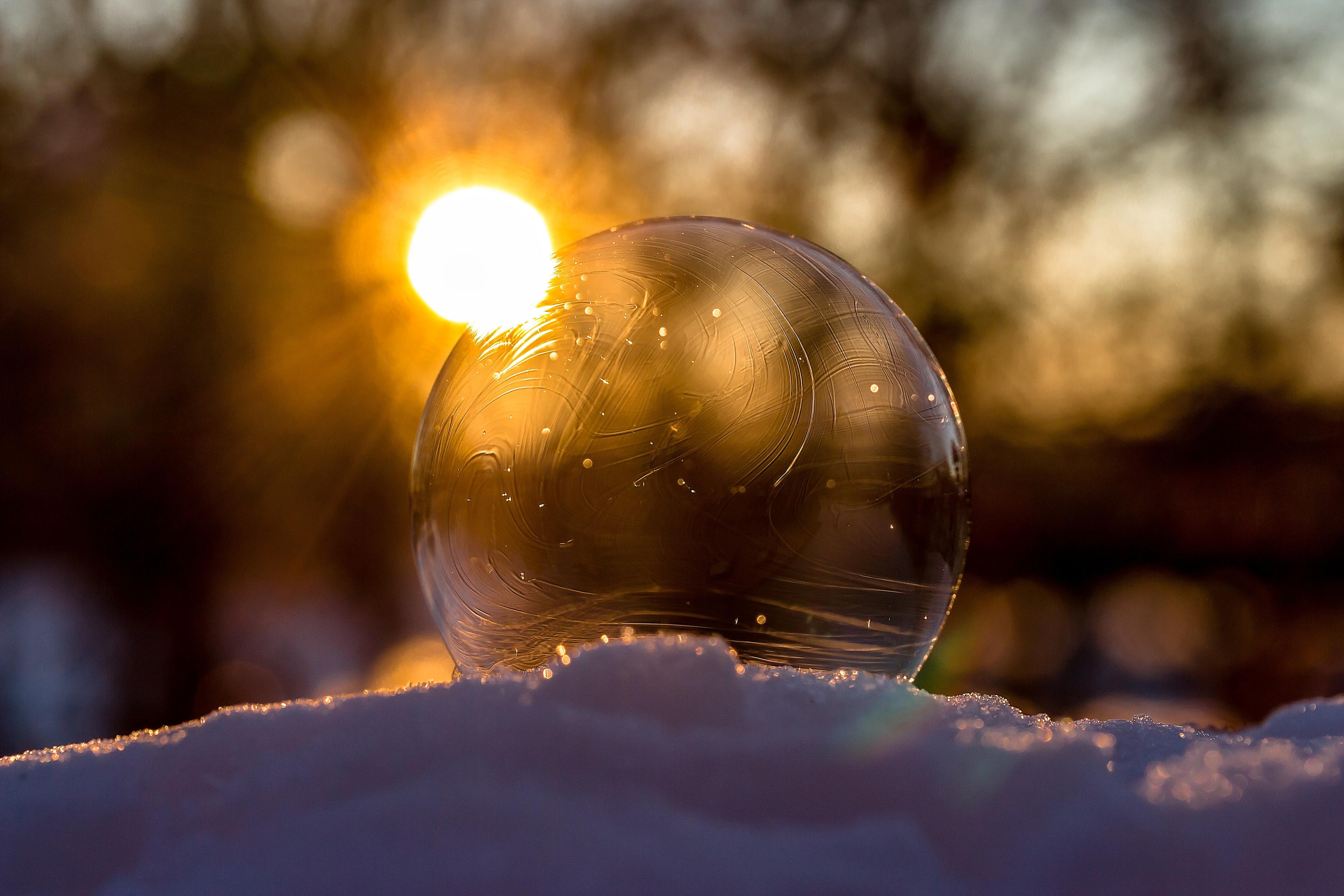 A glass orb resting on the snow with a sunset in the background