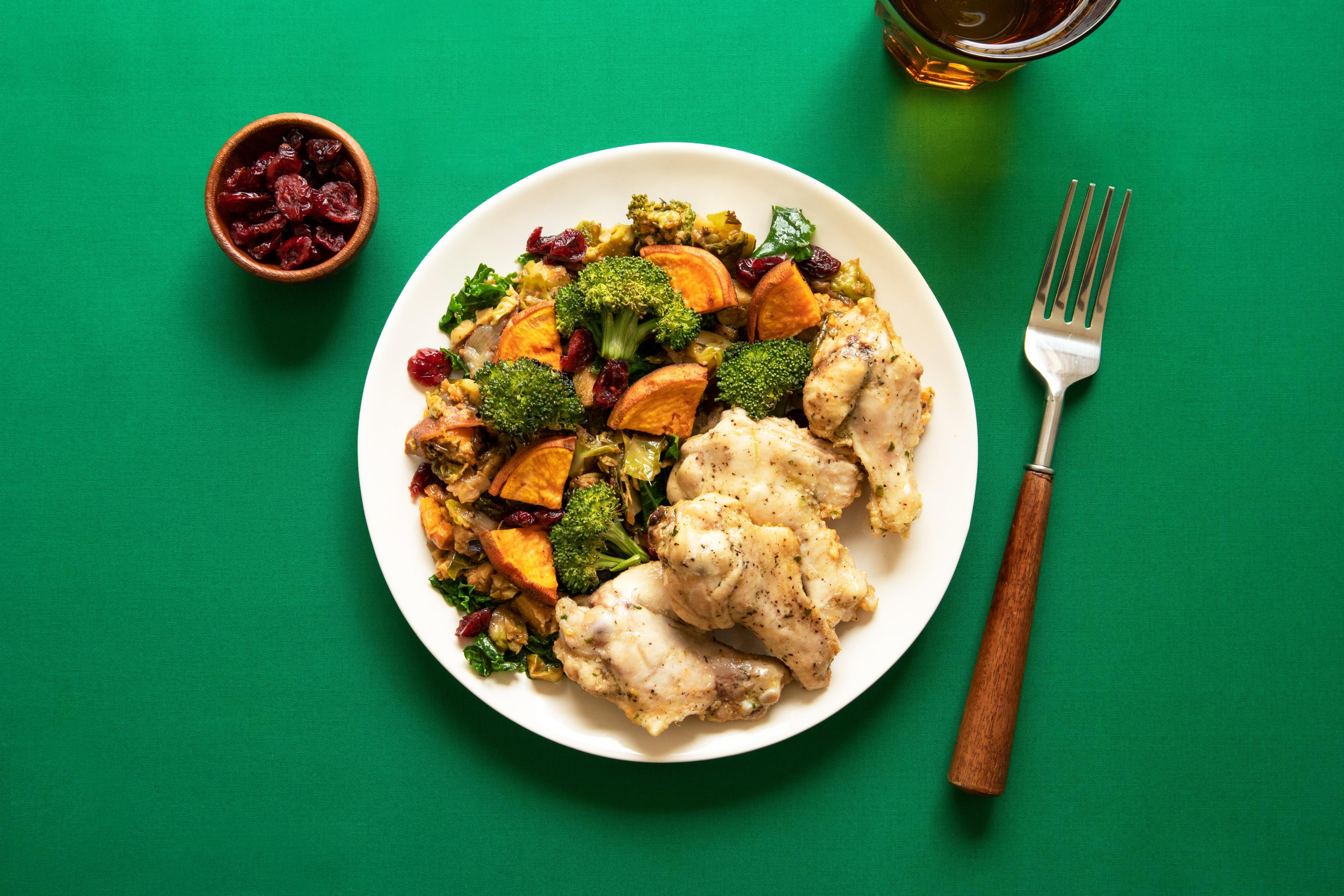 A plate of chicken and vegetables on a green background