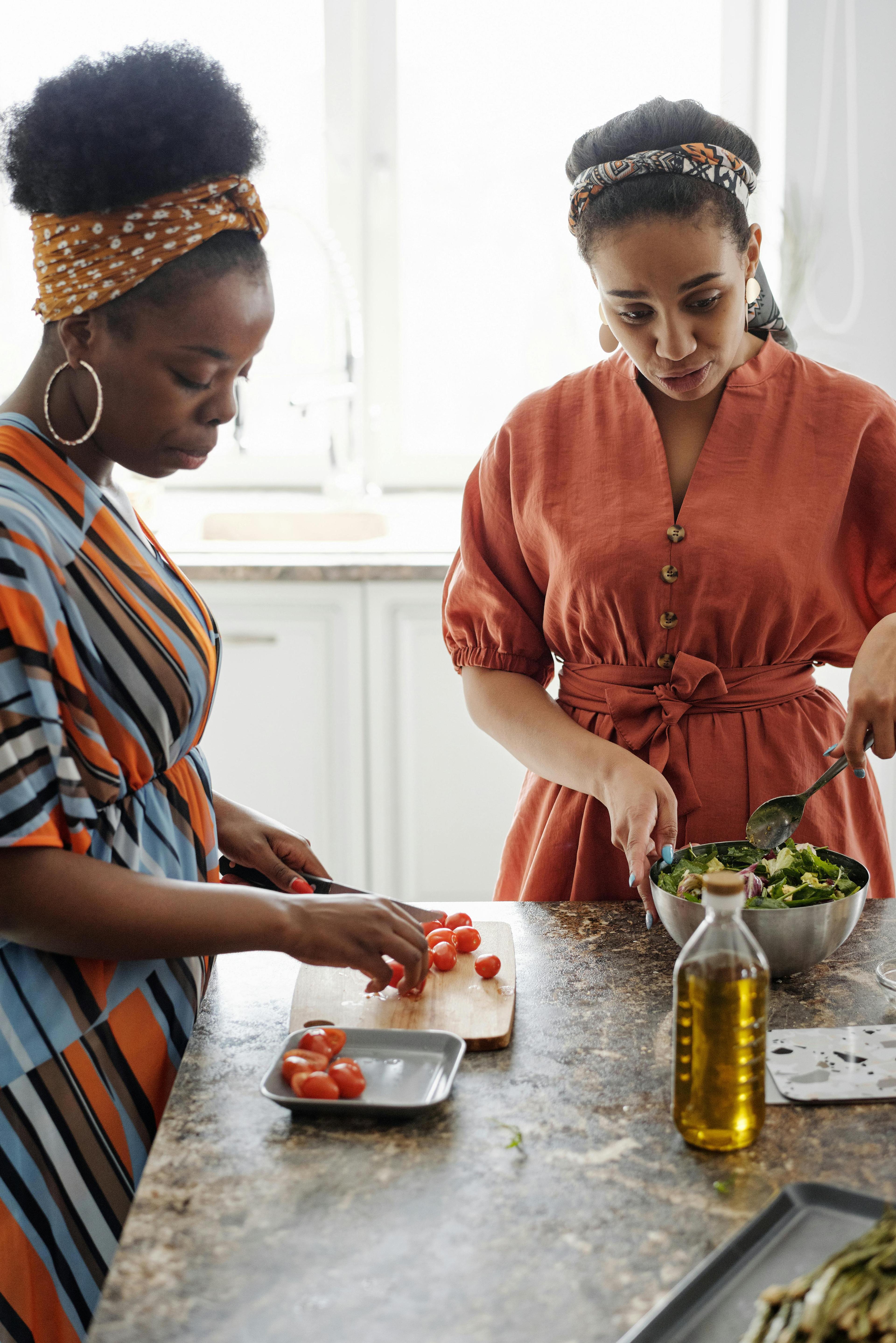 Two black women prepare food at a kitchen counter