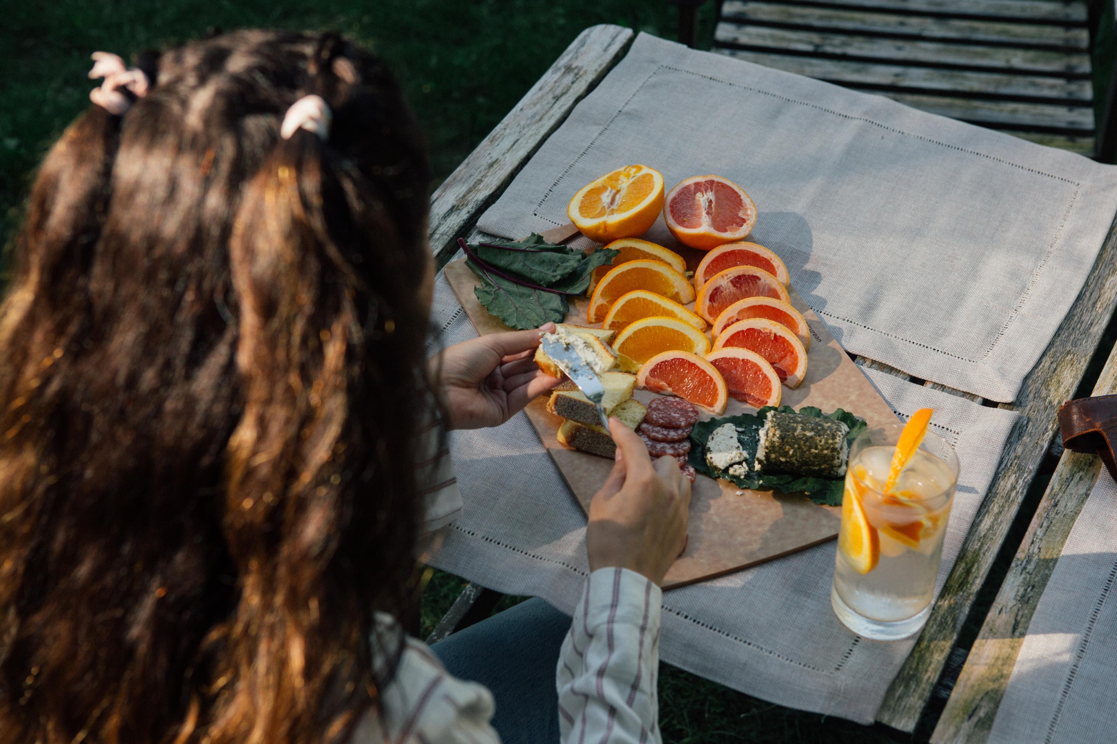 A girl with her back to the camera eating a snack of goat cheese and sliced oranges