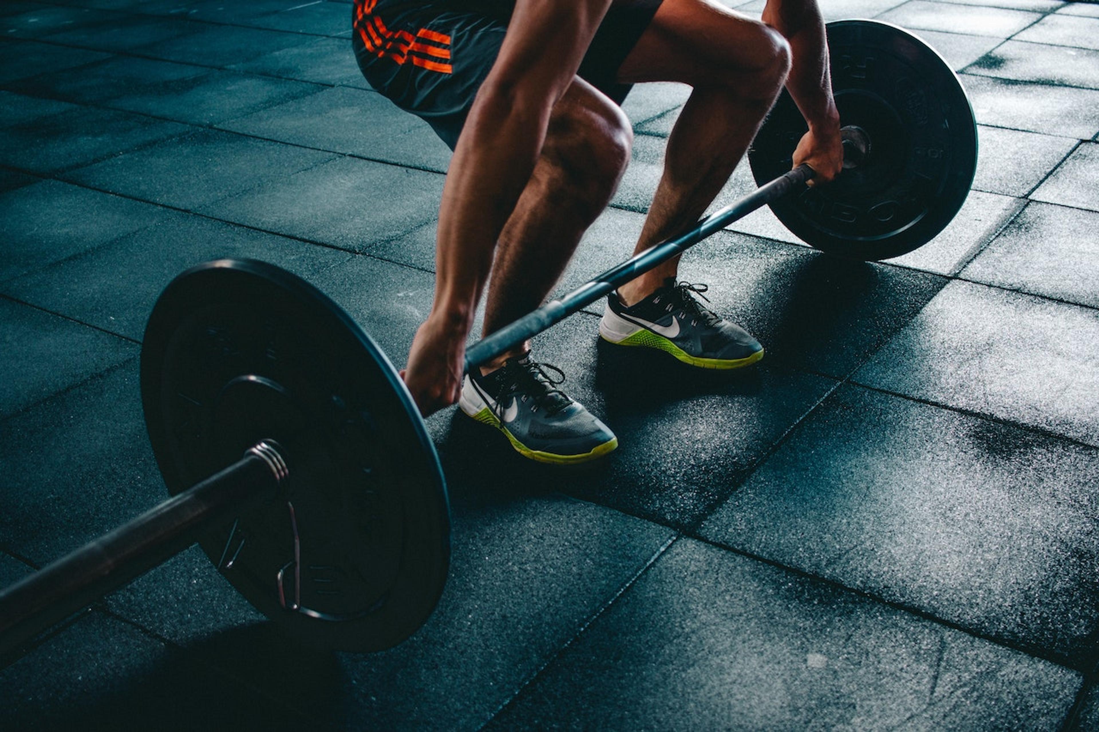 A man bends down to pick up a barbell at the gym