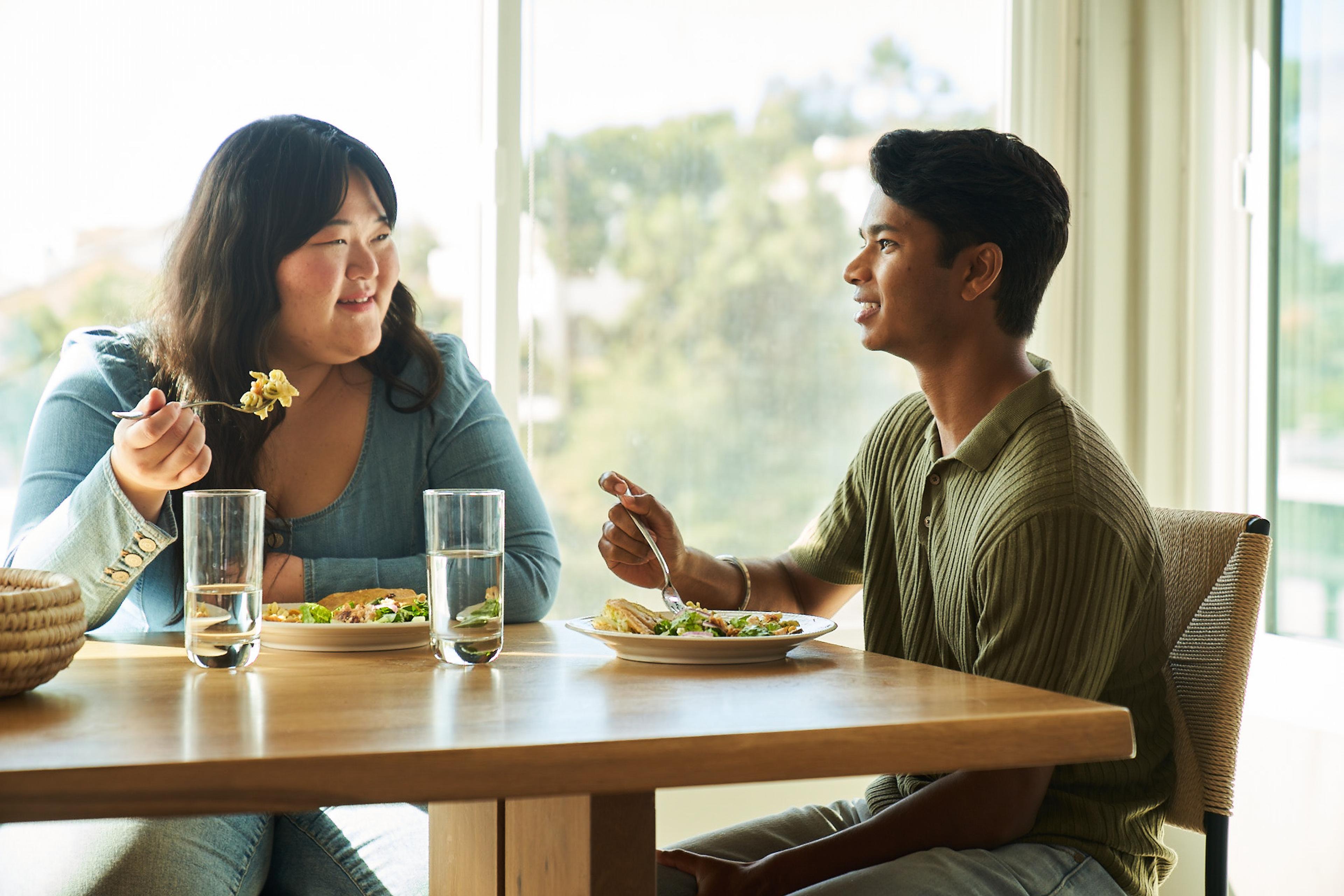 Two people sharing a meal together in a brightly lit room.