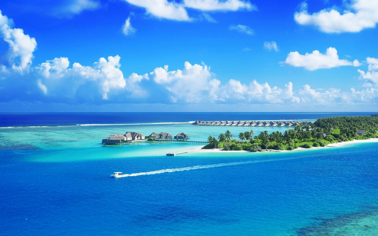 Crystal clear waters surround a luxurious Maldives resort under a bright blue sky.