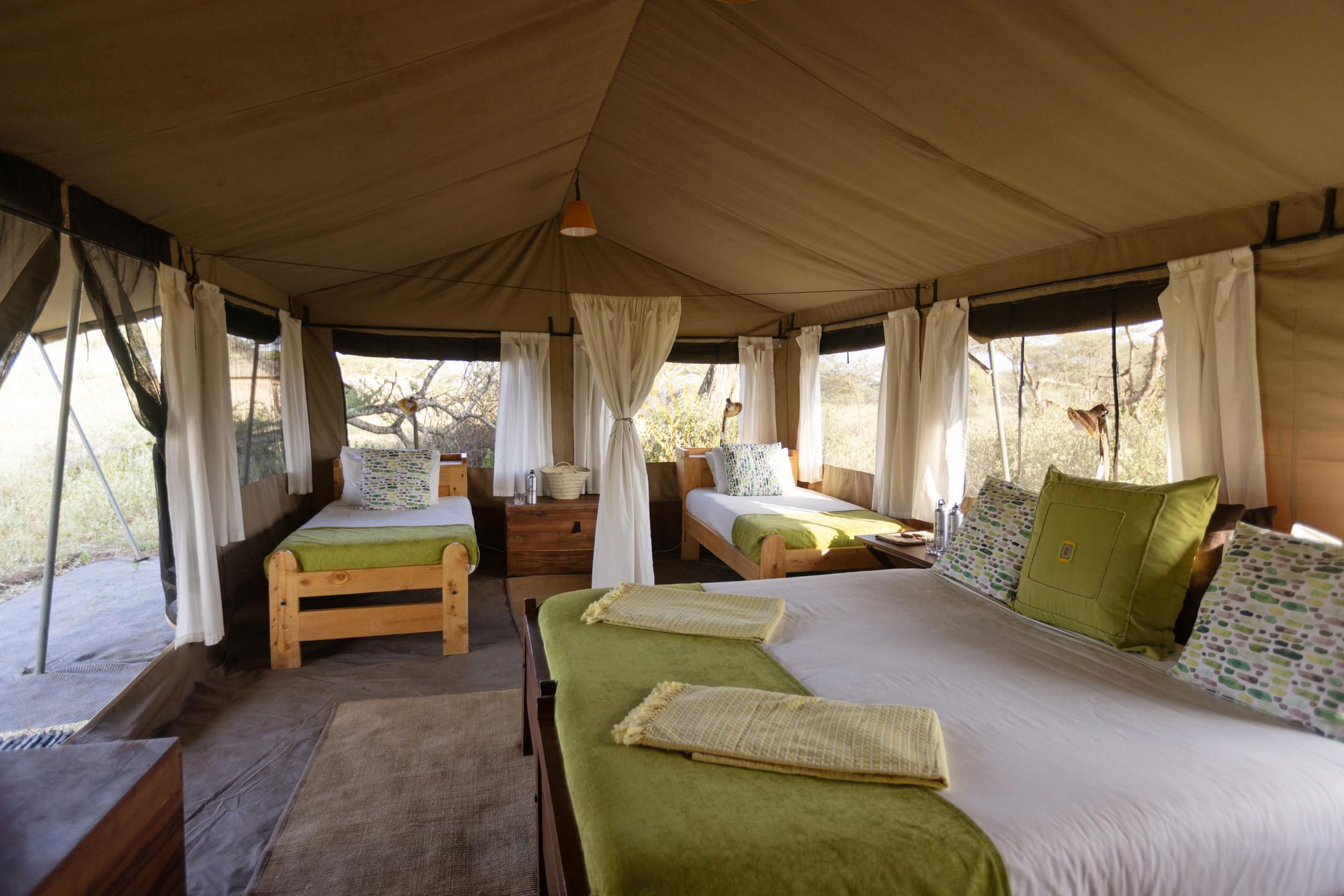 Interior of luxury tent bedroom with double bed and two single beds