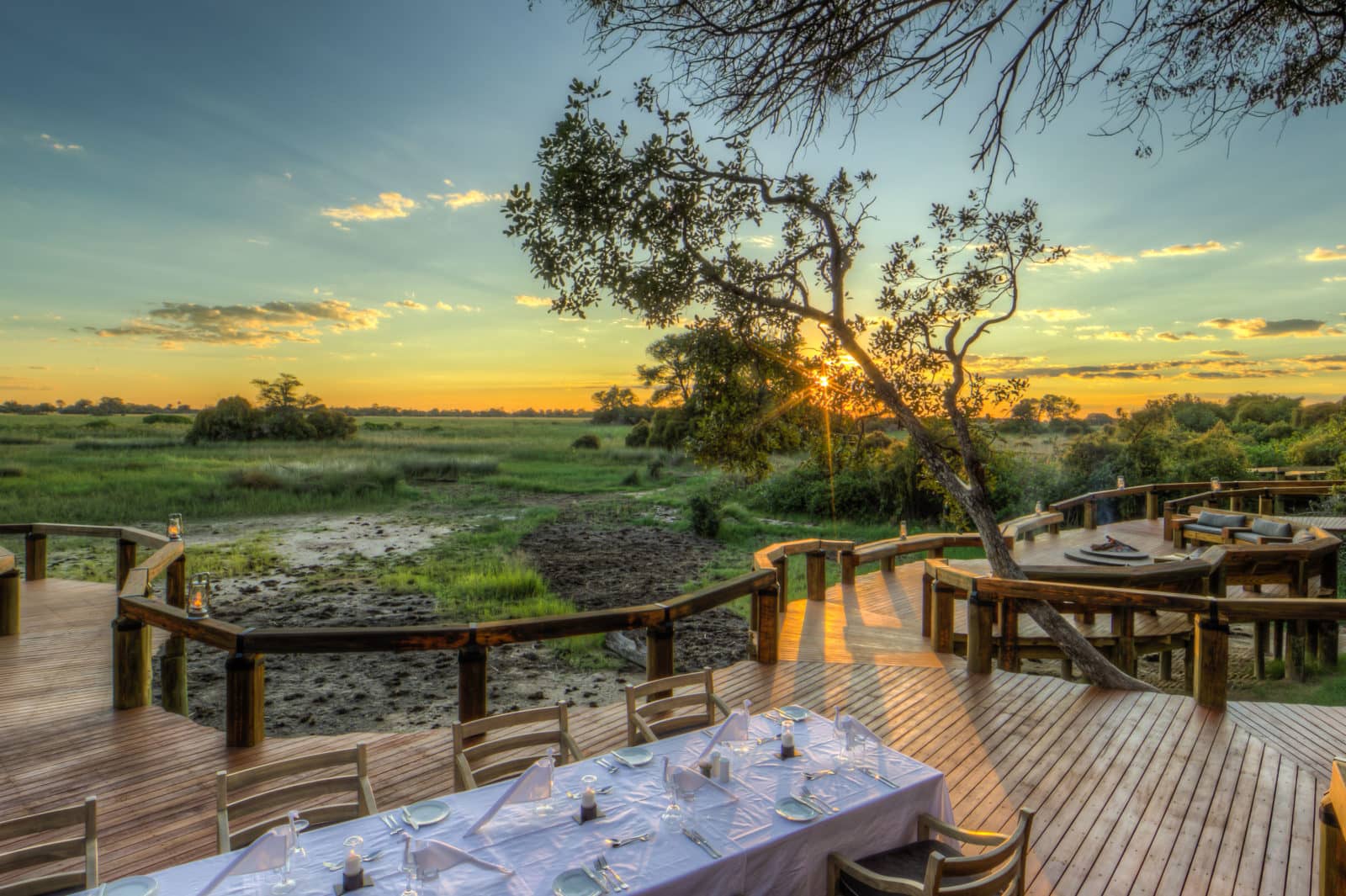 Camp Okavango outdoor dining with sunsetting over Delta