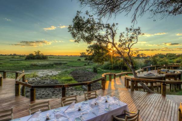Camp Okavango outdoor dining with sunsetting over Delta