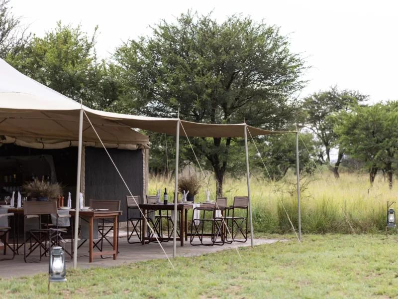 Tented lodge with dining tables and chairs under awning