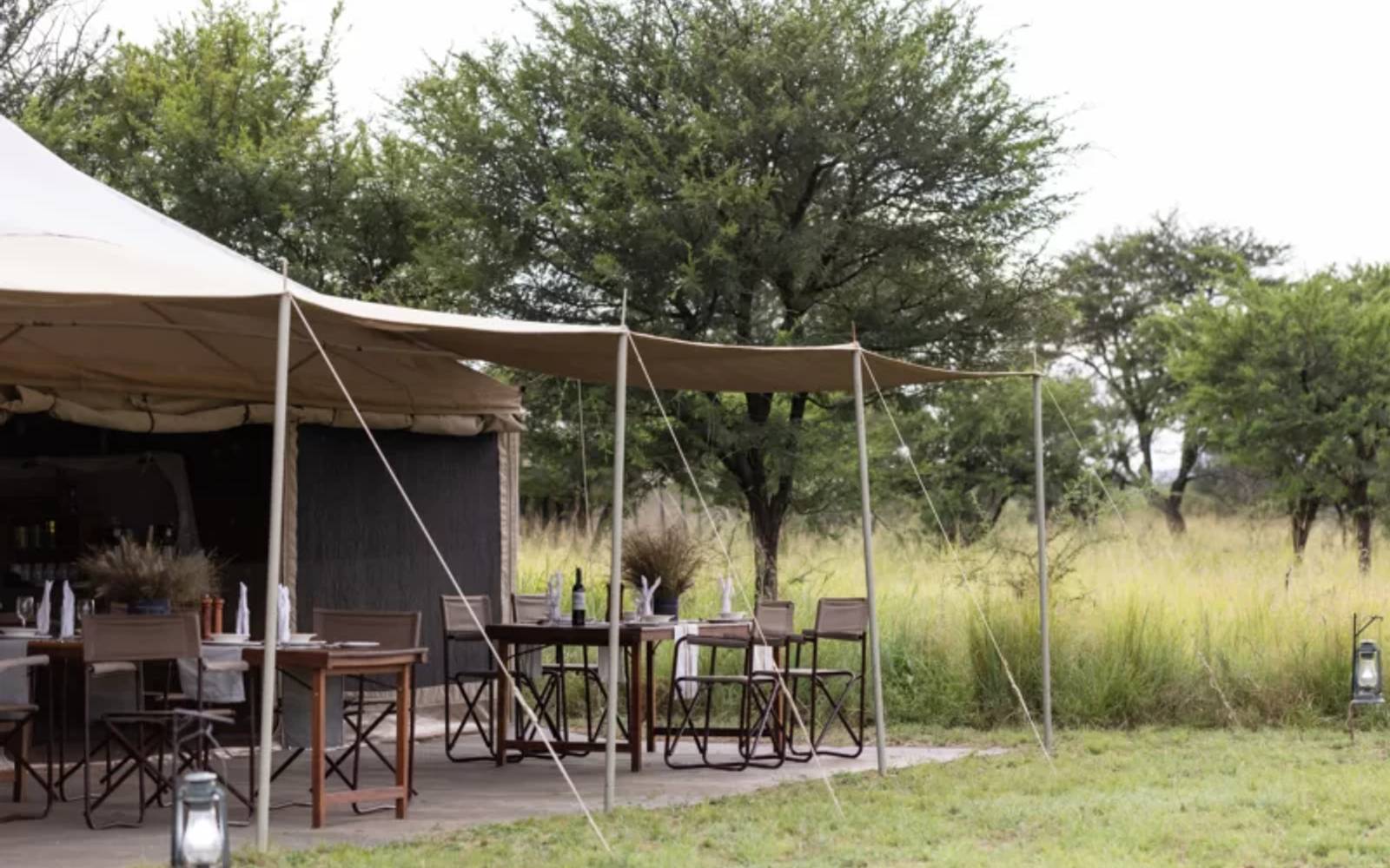 Tented lodge with dining tables and chairs under awning