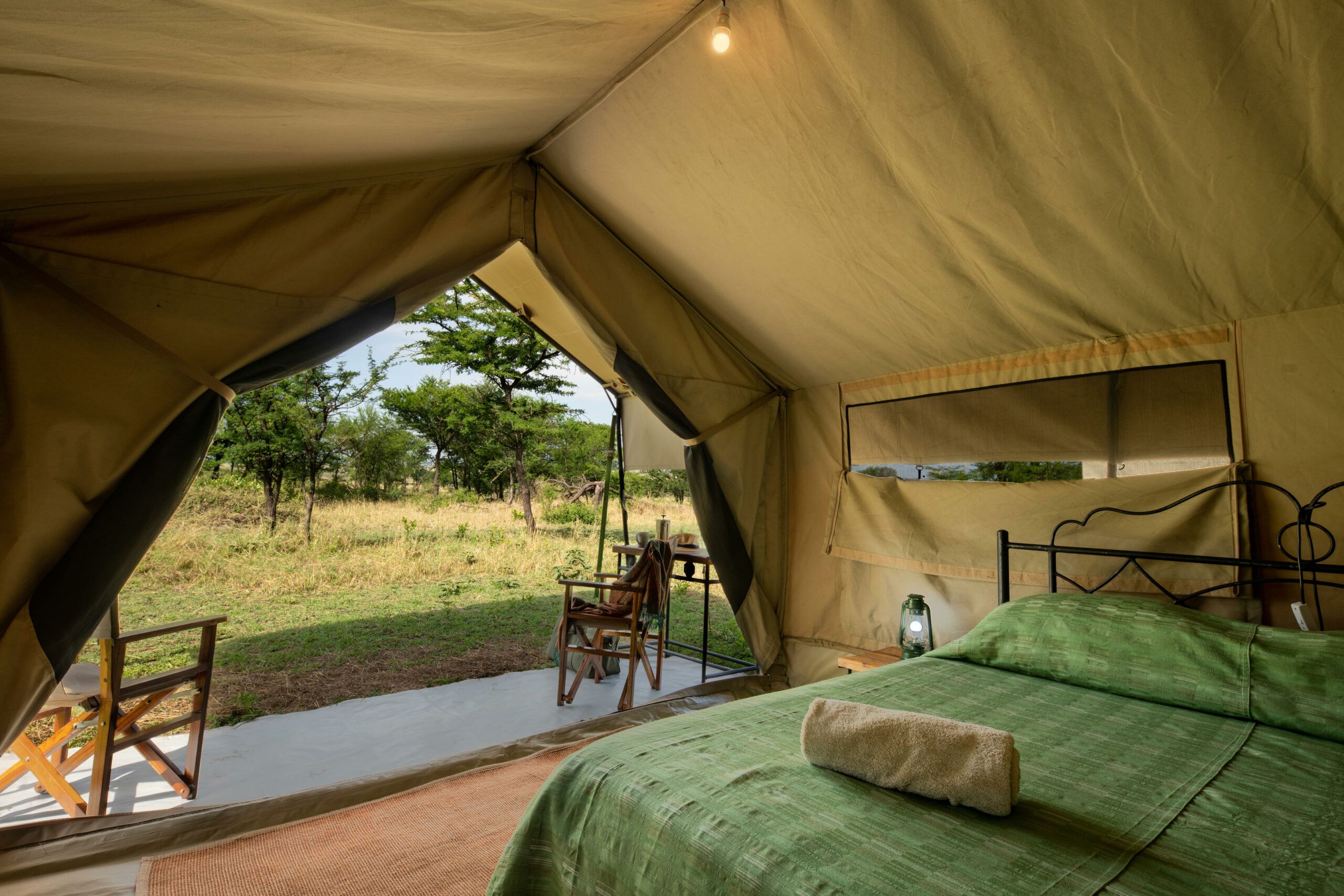 Double bed inside tented luxury camp overlooking African bush