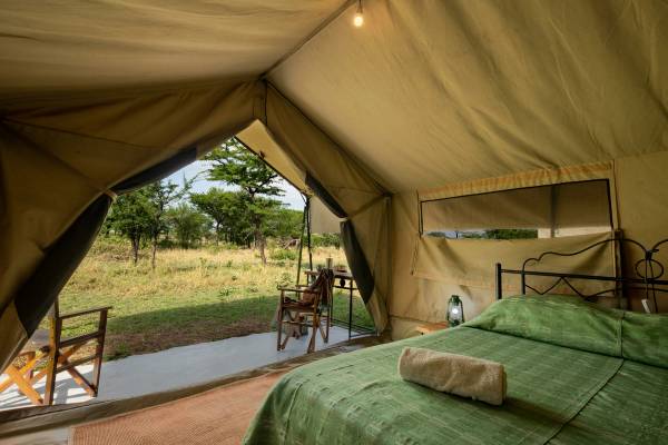 Double bed inside tented luxury camp overlooking African bush