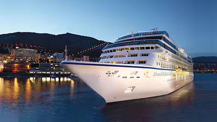 Ship Exterior – Sirena docked at port, illuminated at dusk