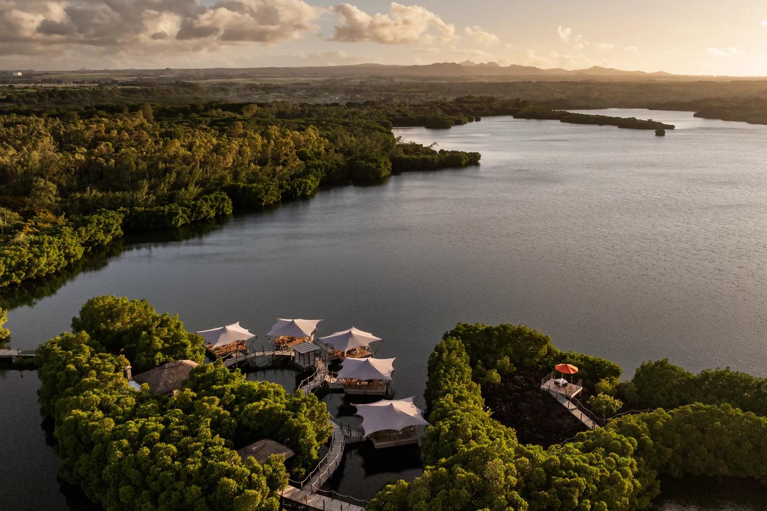 Overwater chalets and green island land next to calm water
