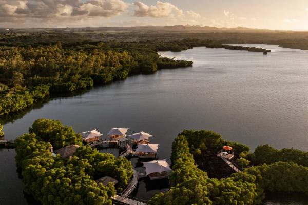 Overwater chalets and green island land next to calm water