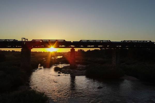 Bridge over river with stationary train and sun setting in the background