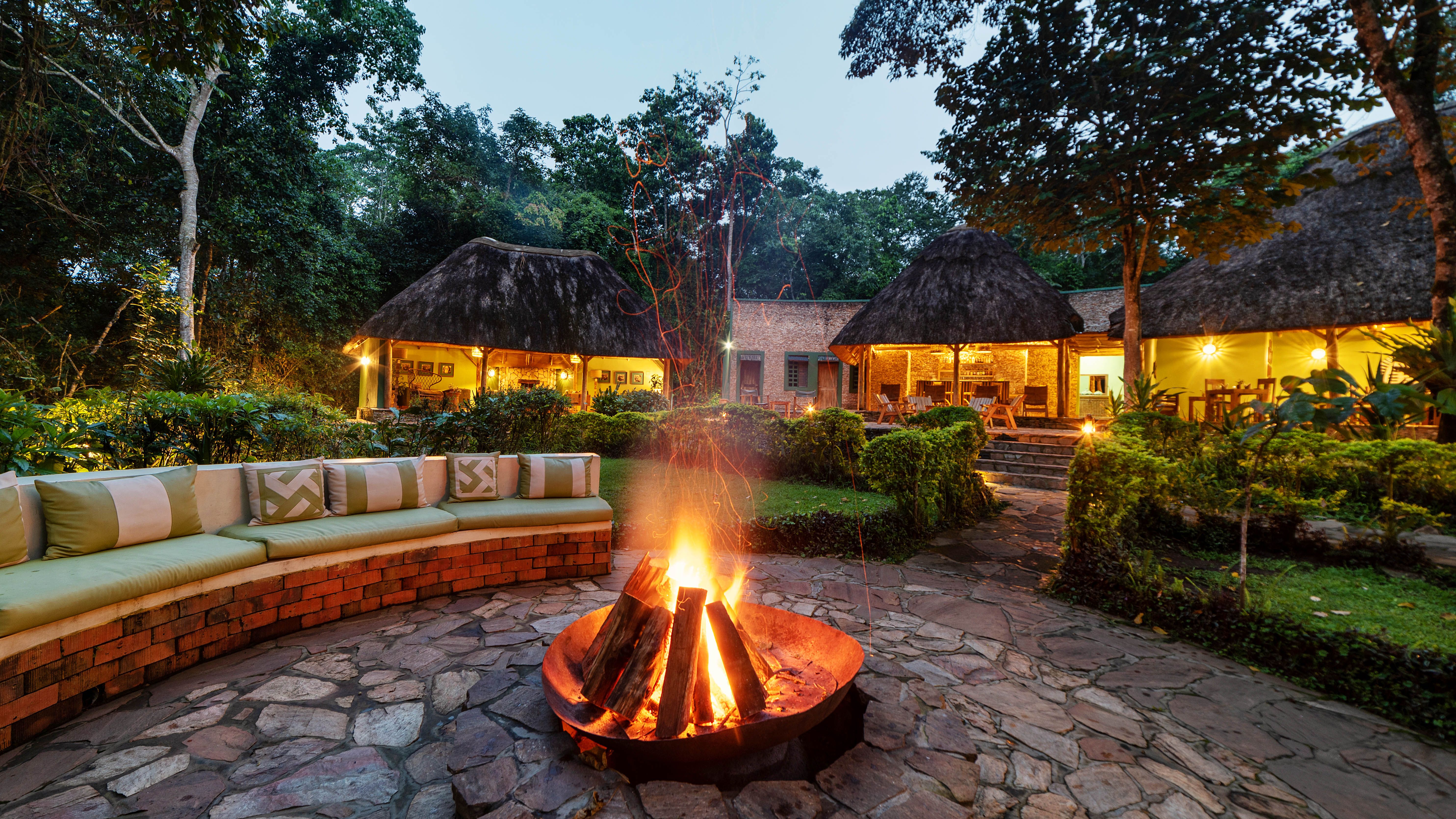 Open fire place with seating around and thatched chalets in the background