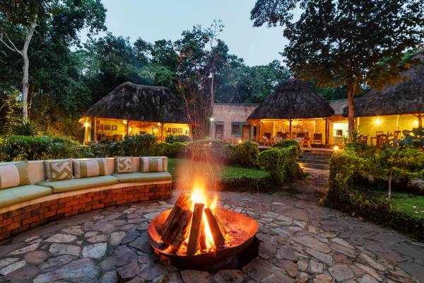 Open fire place with seating around and thatched chalets in the background
