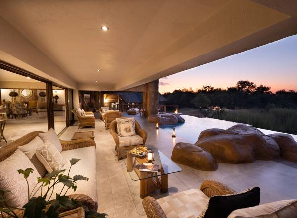 Kingfisher Villa lounge area illuminated at night with rock features overlooking grassland