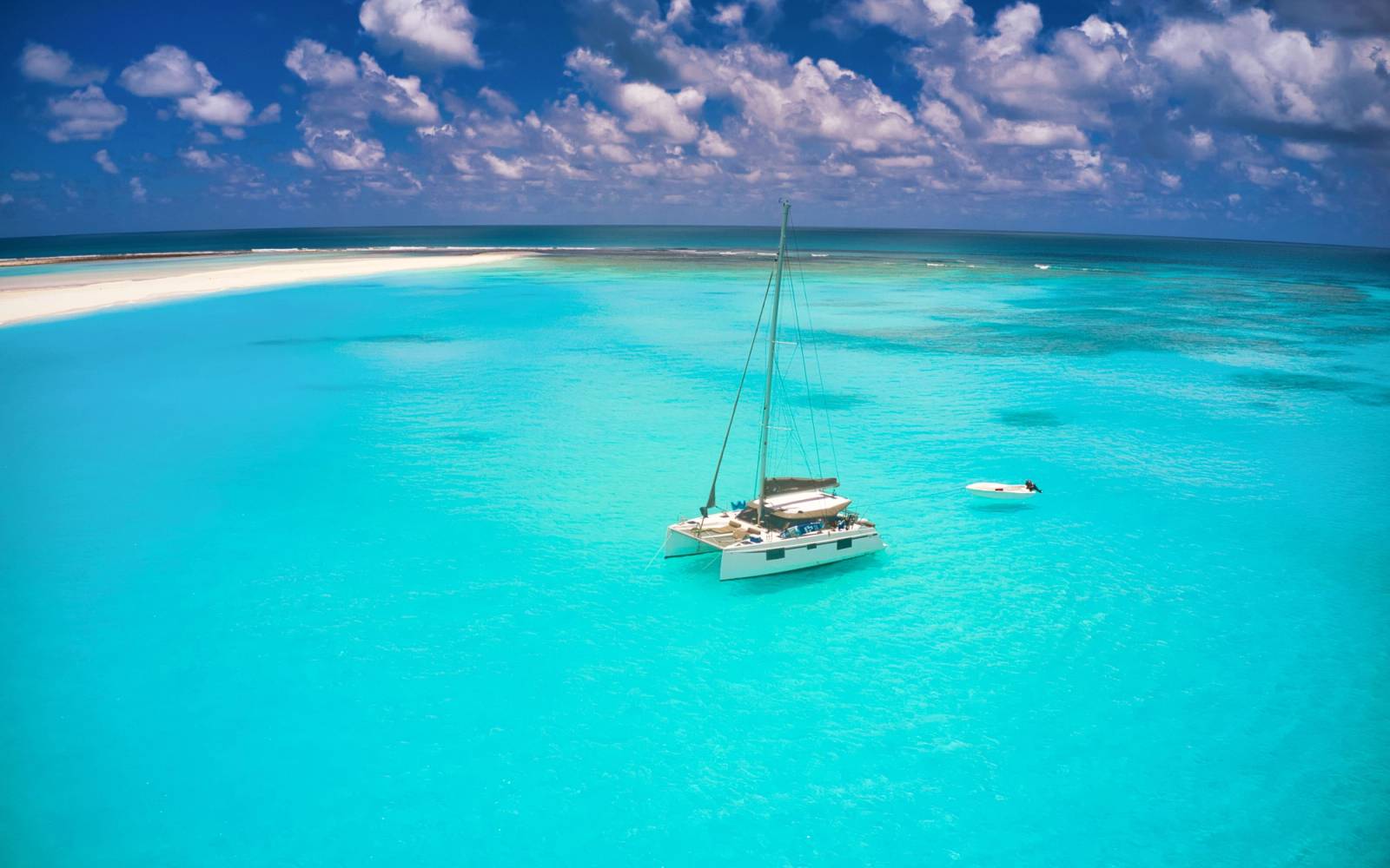 A scenic aerial shot of a sailboat and a sandbar in the turquoise waters of Mauritius.